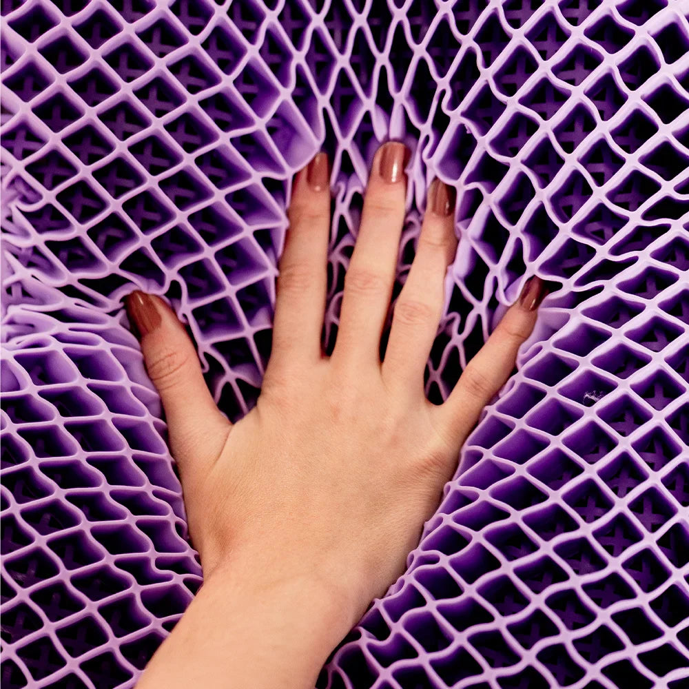 Nãos femininas com unhas pintadas em tom nude tocando em sua exclusiva estrutura construtiva do airgelly® na cor roxa que garante uma distribuição uniforme da pressão da cabeça e pescoço, ajudando a aliviar e prevenir dores causadas por pontos de tensão.
